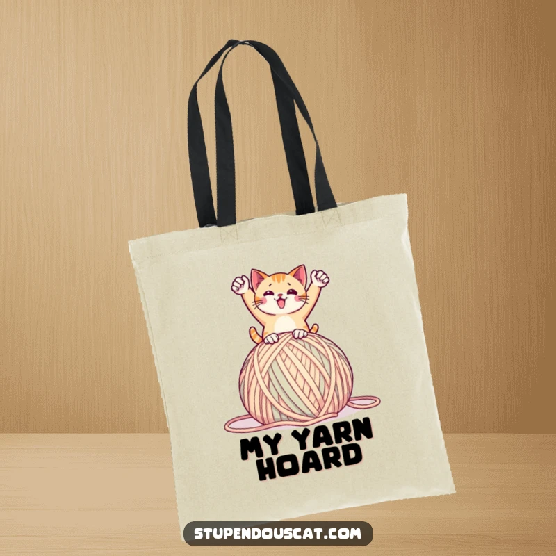 Funny tote bag featuring a cat in a triumphant pose on a giant ball of yarn, perfect for carrying essentials with playful humor, a great gift.