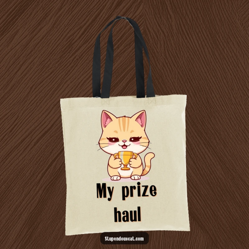 Funny cat tote bag showing a smug cat holding a tiny trophy, ideal for shopping and carrying essentials.